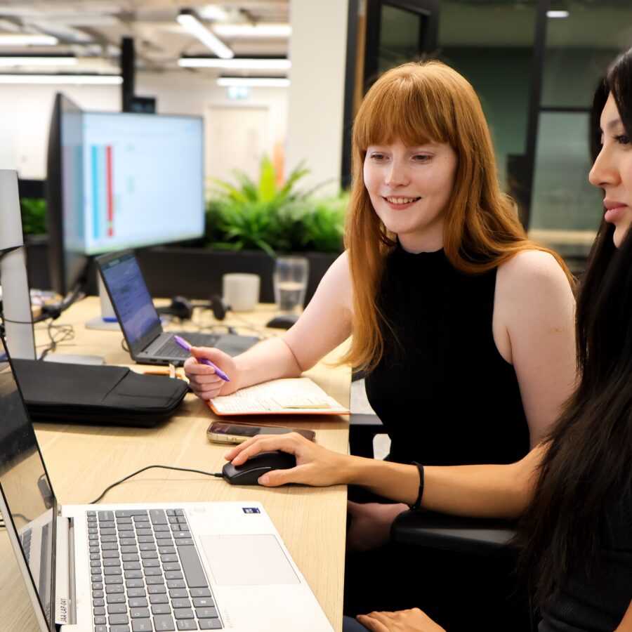 Two members of teh JAA search team sit in front of a laptop with screens around them. One colleague has her hand on a computer mouse.