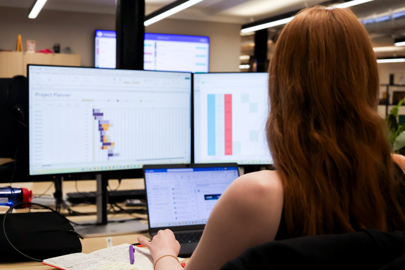 Paid Search team meber is working with thress screens infront of her.