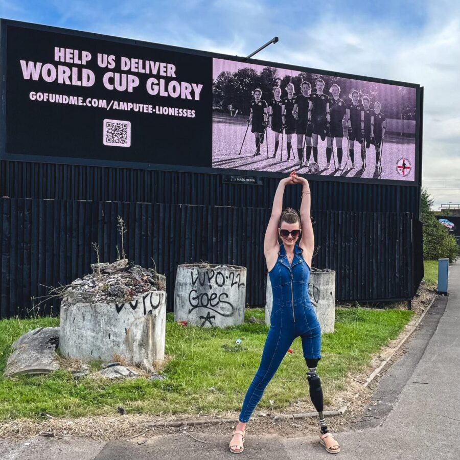 One of the Amputee Lionesses stands in front of campaign image featured on billboard