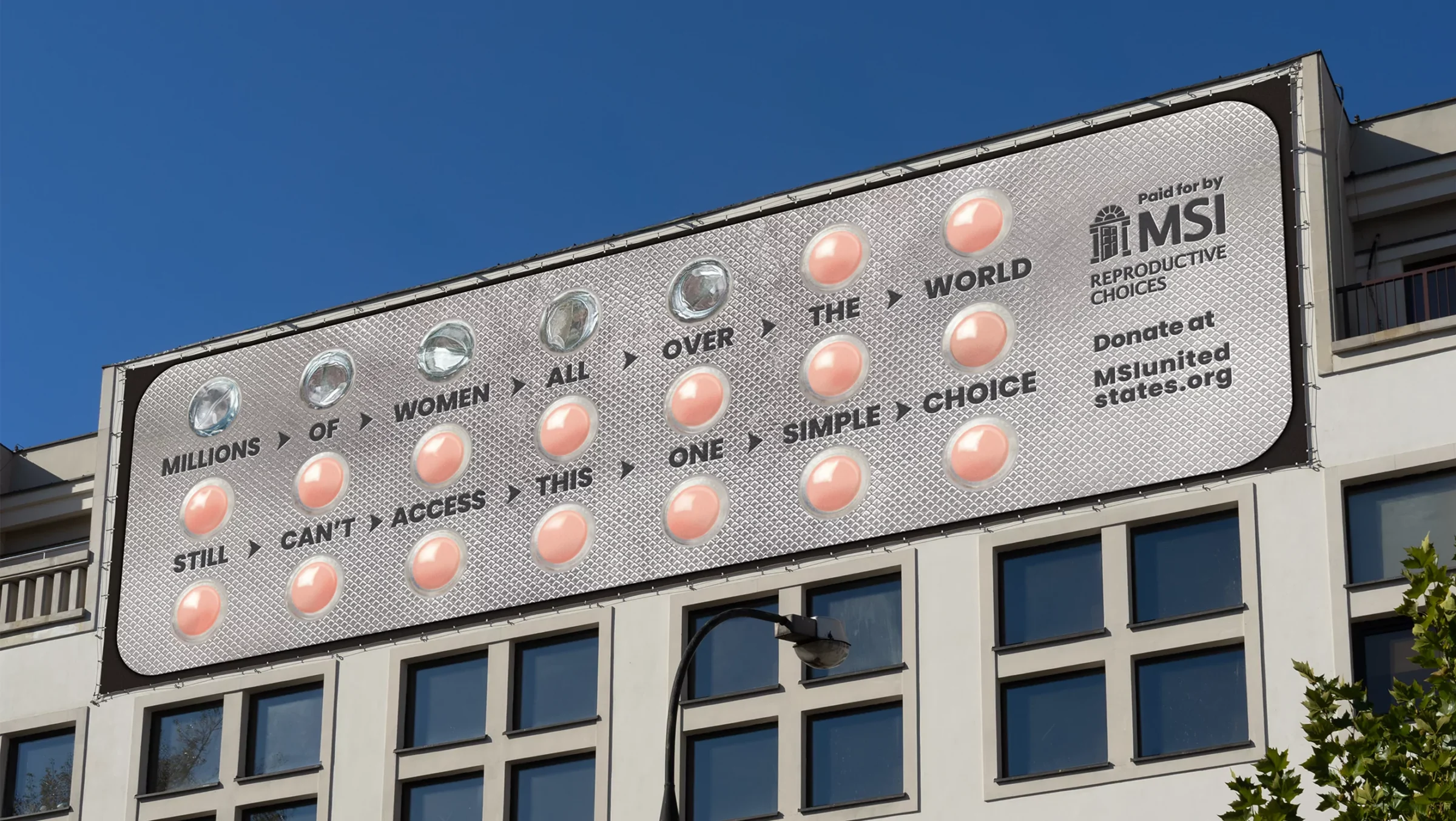 The MSI 'pillboard' shows a billboard on a building reading, “Millions of women all over the world still can’t access this one simple choice,” against a clear blue sky.