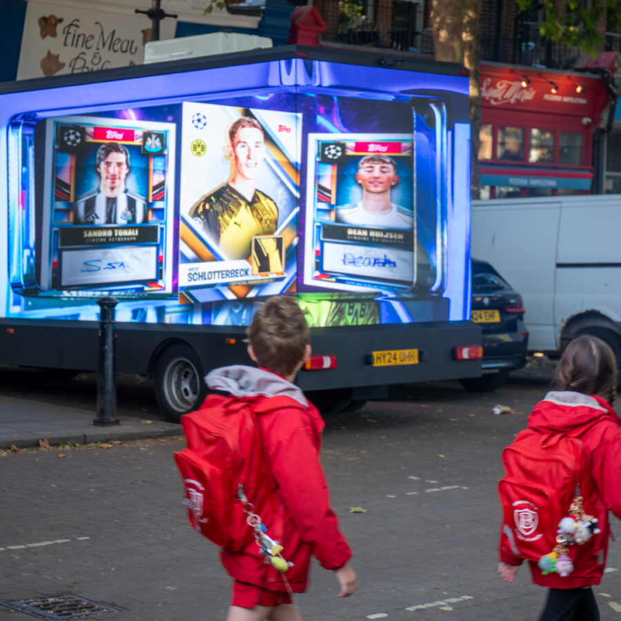 Some school children walk past a digital ad van