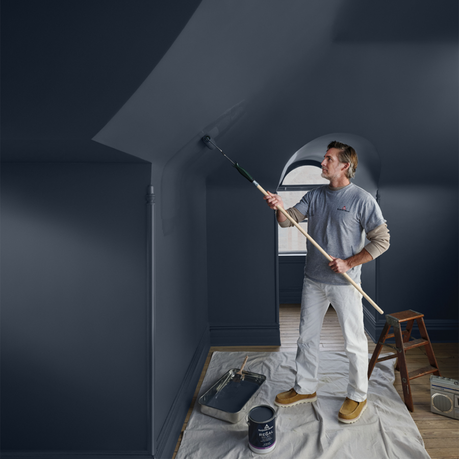 A contractor is painting a wall a dark blue colour using Benjamin Moore paints