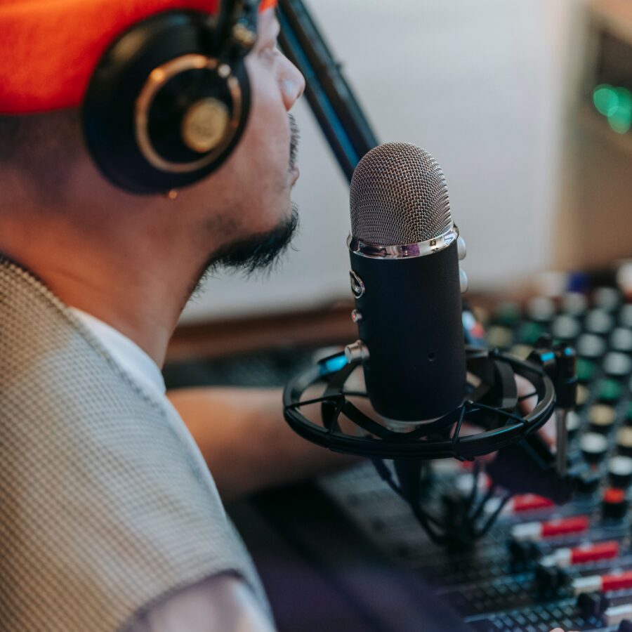 Radio DJ with an orange hat sits over a mixing desk