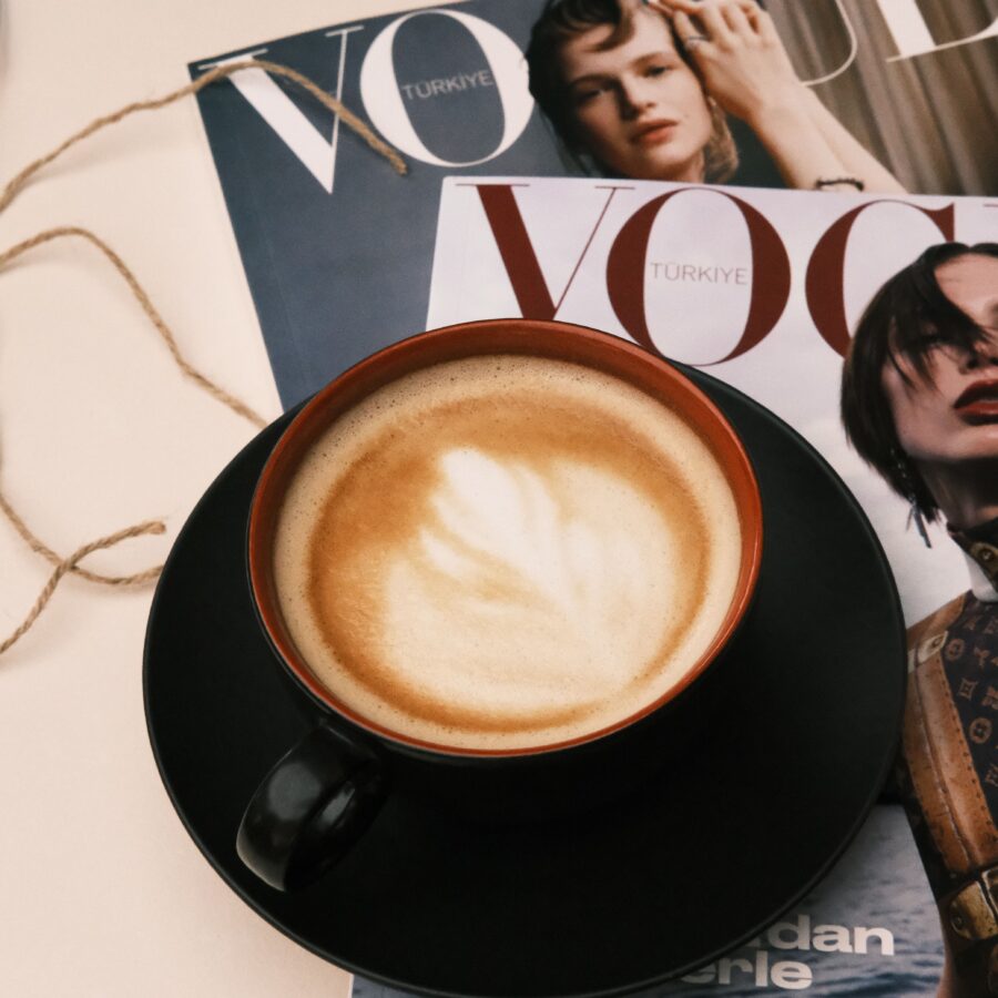 A cappuccino coffee is placed on top of two copies of Vogue