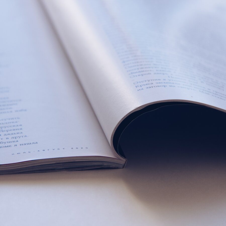A newspaper Supplement magazine is folded over whilst on a wooden table