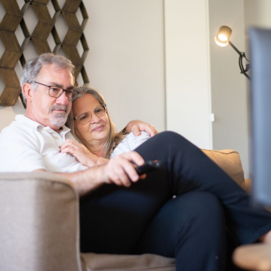 A midlife couple are sat on the sofa watching the TV